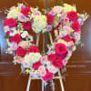 Heart-shaped floral arrangement of pink and cream roses on an easel