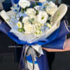 Bouquet of white roses and pale blue flowers wrapped in blue paper