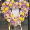Heart-shaped floral wreath of roses in pink, lavender, white, and yellow