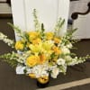 Yellow and white floral arrangement in a black vase with a yellow ribbon