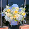 Large bouquet of blue, white, and yellow roses in a round box