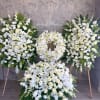 White floral funeral wreaths and sprays on stands with a large floor arrangement