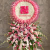 Pink and white funeral standing spray with a circular floral tribute above it
