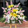 Large mixed bouquet with yellow lilies, pink roses, and orchids in a white vase