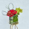 Red and green floral arrangement in a clear glass vase
