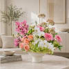 Mixed pink, white, and peach flowers arranged in a white vase