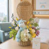 Basket arrangement with a plush giraffe and mixed flowers