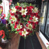 Beautiful sympathy heart with roses and lilies accompanied by greenery.