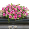 Pink rose and carnation casket spray arranged on a dark metal casket