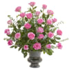 Tall arrangement of pink roses in a dark pedestal vase