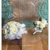 Two small white rose boutonnieres with feather accents