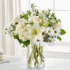 White flowers arranged in a clear glass vase with green accents