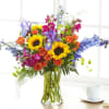 Colorful bouquet of sunflowers, roses, and irises in a clear glass vase