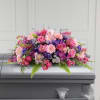 Pink and purple floral spray arranged on a casket