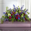 Casket spray with blue, purple, and pink flowers