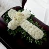 White floral cross arrangement on a dark casket