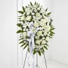 White floral standing spray with a ribbon on a black easel