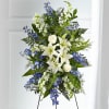 Standing floral spray with white lilies, white roses, and blue flowers