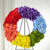 Rainbow floral wreath on a black stand with red, purple, blue, yellow, and green sections