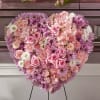 Heart-shaped floral arrangement of pink and lavender blooms on a stand