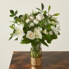 White lilies and roses in a glass vase with green foliage