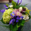 Bouquet of purple irises, hydrangeas, and mixed blooms in a basket