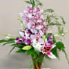 Tall bouquet of pink and purple orchids in a glass vase
