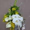 White orchids and calla lilies with yellow accents in a tall vase arrangement