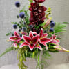 Tall floral arrangement with pink lilies, burgundy orchids, and blue thistle in a vase