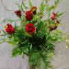 Red roses in a clear glass vase with airy greenery