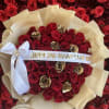 Round bouquet of red and gold roses wrapped in cream paper with a white bow and printed anniversary ribbon