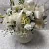 White floral arrangement with roses, carnations, and a satin ribbon in a vase