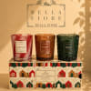 Three scented candles in decorative glass holders on a holiday gift box