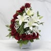 Red roses and white lilies arranged in a clear square vase