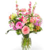 Mixed pink and peach flowers arranged in a clear glass vase