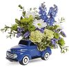 Blue toy truck filled with white, blue, and green flowers