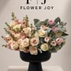 Cream and pink roses with ranunculus in a black pedestal vase