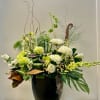 Tall floral arrangement with white and green blooms in a black vase