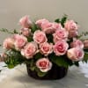 Pink roses arranged in a dark basket with greenery