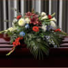 Casket spray with red, white, blue, and cream flowers