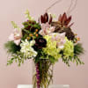 Mixed floral arrangement in a clear glass vase with pink orchids and green hydrangeas