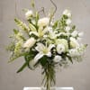 White lilies and roses arranged in a clear glass vase