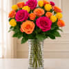 Bouquet of pink, orange, and yellow roses in a clear glass vase