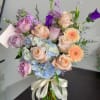 Bouquet of pastel roses, hydrangeas, and purple blooms in a glass vase