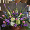 Basket arrangement of pink and purple flowers with white blooms
