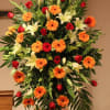Large standing floral spray with red roses, orange gerberas, and white lilies