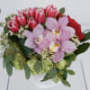 Bouquet of pink tulips, orchids, and red roses in a white vase