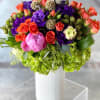 Colorful bouquet of roses and purple blooms in a white vase