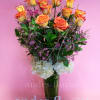 Orange-yellow roses in a tall vase with white hydrangeas and purple filler flowers