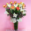 Bouquet of orange-edged roses and white lilies in a tall vase